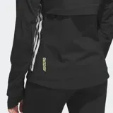 Campera rompevientos Adidas de running, color negro con las clásicas tres tiras blancas en los costados y logo reflectante. Cuenta con cierre frontal, capucha con cordón ajustable, bolsillo en el pecho y diseño entallado con puños con ojal para el pulgar.