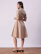 Vestido camisero blanco de algodón con cuello con solapa, delantera abotonada, mangas 3/4 regulables con presilla y botón, y cintura con lazo de ajuste.