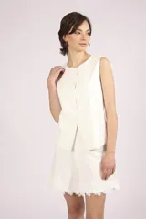 Chaleco blanco sin mangas, con cuello redondo y cierre frontal de botones. El chaleco tiene un corte recto y ligeramente holgado.