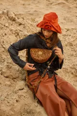 Bandolera de cuero con forma de media luna y estampado animal print. Cuenta con cierre superior, herrajes metálicos dorados y correa regulable para llevar al hombro o cruzada.