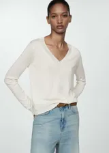 Buzo de punto fino en color blanco, con cuello en pico y manga larga. Presenta terminaciones en canalé en puños y ruedo.