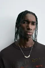 Camiseta negra de algodón con corte boxy fit y cuello redondo. Presenta un estampado gráfico desgastado con temática espacial o celestial en tonos azules y blancos, y texto en la parte superior e inferior.