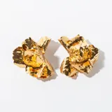 Aros colgantes dorados con forma de flor con textura irregular.