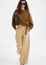 Pantalón recto de tiro medio color beige, confeccionado en mezcla de lino y viscosa. Cuenta con detalle de pinzas, bolsillos laterales y cierre frontal oculto con cremallera, botón y ganchos con tapeta.