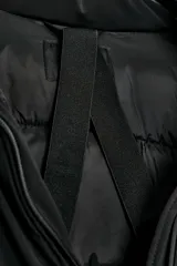 Chaqueta acolchada de color negro, resistente al agua y al viento, con aislamiento térmico. Presenta cuello subido con capucha, cierre frontal con cremallera termosellada de doble cursor, bolsillos laterales con forro polar y puños interiores elásticos.