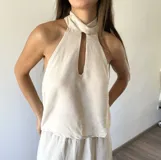 Blusa tipo musculosa de cuello halter con abertura frontal tipo gota, confeccionada en tejido ligero color crudo.