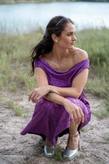 Vestido midi color violeta con textura brillante, escote off-shoulder y mangas cortas.