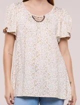 Blusa estampada en tonos de azul y blanco, con escote redondo, aplique artesanal bordado en el centro del pecho, mangas cortas tipo mariposa con volados y ruedo asimétrico.