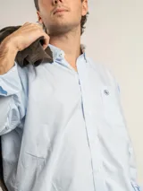 Camisa de corte clásico confeccionada en algodón, con diseño de cuadros finos en tonos neutros. Presenta cuello con botones, bolsillo frontal con logo bordado y cierre de botones.