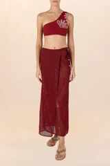 Falda pareo larga color vino, de tejido calado con bordado floral y detalle de cuentas en los pliegues.