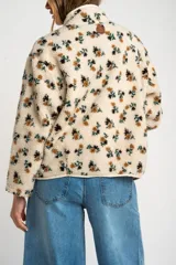 Campera de corderito con estampado floral, cuello alto y cierre frontal con botones a presión. Posee puños elásticos y un diseño de ajuste al cuerpo.
