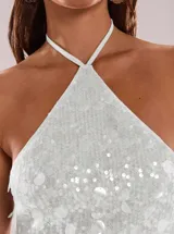 Vestido corto plateado de lentejuelas con escote halter y diseño ajustado.