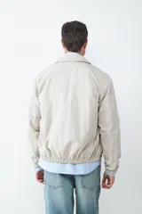 Campera de estilo casual con cuello tipo solapa, cierre frontal de cremallera y bolsillos laterales. Presenta puños y ruedo elásticos, con un acabado de textura ligera.