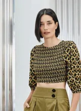 Blusa corta con estampado geométrico en tonos negro y dorado, con mangas 3/4 abullonadas y escote redondo con fruncido elástico.