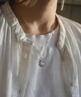 Collar plateado con dije en forma de margarita con múltiples pétalos.