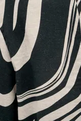 Top de escote redondo y manga corta, con corte asimétrico en la espalda. Confeccionado en lino viscosa, con estampado abstracto en blanco y negro.