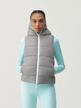 Chaleco acolchado reversible con capucha, cierre frontal de cremallera y bolsillos laterales. Diseño cortavientos y funcional con relleno vegano.