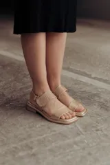 Sandalia Roma de cuero dorado, con tiras anchas, una lisa en la puntera y otra con textura reptil en el empeine, y tira ajustable al talón con hebilla. Suela plana y cómoda.