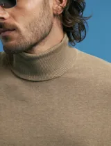 Polera de punto de manga larga en color azul marino, con cuello alto doblado y puños y ruedo acanalados.