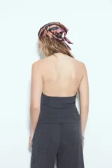 Top de cuello halter color gris oscuro, con escote en V pronunciado en el frente y espalda descubierta. Presenta textura acanalada.