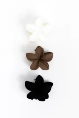 Pack de tres pinzas para el cabello con diseño en forma de flor, en colores blanco, marrón y negro.
