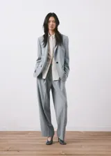 Blazer de corte sastrero en color gris azulado, con cierre frontal de un botón, solapas clásicas y bolsillos laterales con solapa.