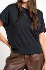 Remera negra de corte oversize, con mangas cortas y cuello redondo, confeccionada en tejido de viscosa y elastano de caída fluida.