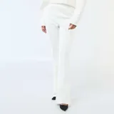 Pantalón de corte recto y ligeramente acampanado, confeccionado en felpa ligera color blanco. Presenta costuras verticales frontales que estilizan la silueta y un diseño fluido.