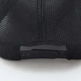Gorra negra con visera curva y paneles traseros de malla. Presenta un bordado frontal con un paisaje de montañas y el texto "Wyoming Mountains".