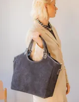 Bolso tipo shopper de gamuza color negro, forrado en su interior. Cuenta con asas de mano y una correa larga desmontable para llevar al hombro o cruzado.