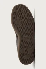 Zapatilla deportiva de estilo retro, confeccionada en una combinación de piezas de cuero texturizado y gamuza en tonos marrones. Presenta un diseño de doble cordonera con cordones claros y suela de goma a tono.