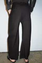 Pantalón de tiro medio con diseño de raya diplomática, confeccionado con cintura con trabillas, bolsillos laterales y cierre frontal con cremallera y botón.