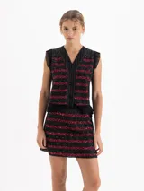 Minifalda negra con bordado frontal de lentejuelas en forma de cerezas, detalle de cinto tejido en lana y volado de organza plisada en el ruedo.