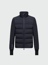 Campera puffer Moncler modelo Agaripe en color azul marino, diseñada con un cuerpo acolchado y mangas de tejido técnico. Incluye cuello alto, cierre frontal de cremallera, puños con orificios para el pulgar y aislamiento PrimaLoft.