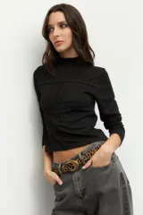 Polera blanca de manga larga con cuello alto y costuras cruzadas a la vista en el frente.