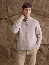 Sweater de punto en color beige, con cuello alto y cierre frontal parcial de botones. Presenta mangas largas con puños acanalados y diseño de corte clásico.