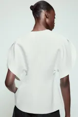 Top de Zara Woman Collection color blanco, con escote en pico, mangas cortas abullonadas con aberturas y cierre frontal con cremallera.