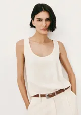 Blusa sin mangas de color blanco, con escote redondo amplio y corte holgado.