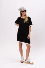 Vestido corto negro de tejido de punto calado, con cuello redondo y mangas cortas con ribete blanco.