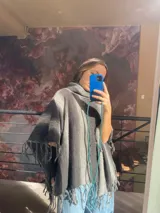Poncho de lana con diseño de rayas horizontales en tonos grises, cuello alto y flecos en todo el borde.