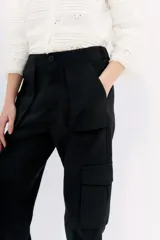 Pantalon cargo negro de calce relajado con ajuste en los tobillos. Cuenta con bolsillos laterales con solapa y cintura con cierre, botón y elástico en la parte posterior.