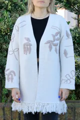 Sacón con flecos color crema, confeccionado en algodón y acrílico. Cuenta con bordados hechos a mano de motivos tropicales en frente, espalda y mangas.