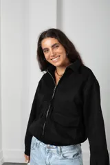 Campera de gamuza negra con cierre frontal, cuello camisero, bolsillos delanteros con solapa y puños con botón.