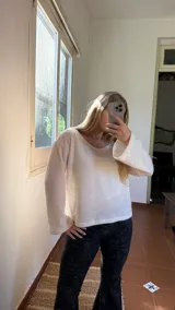 Blusa de punto color crudo con escote amplio, mangas largas acampanadas y corte holgado.