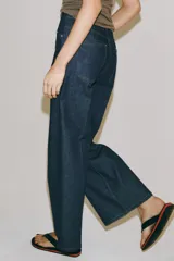Jeans wide leg de tiro alto en color azul oscuro, con trabillas en la cintura, diseño de cinco bolsillos, nervios delanteros marcados y pespuntes a contraste. Cuenta con cierre frontal de cremallera y botón metálico.
