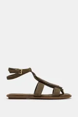 Sandalia plana color verde militar, con tiras de cuero y detalle de flecos en la parte delantera. Tiene pulsera al tobillo con cierre de hebilla metálica y punta redonda.