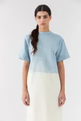 Vestido midi de corte recto, con diseño bicolor en degrade que combina celeste en la parte superior y blanco marfil en la inferior. Posee mangas cortas y cuello redondo.