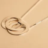 Collar con dije compuesto por tres aros entrelazados de plata 925, con cadena de eslabones tipo veneciana.