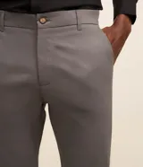 Pantalón slim de sarga color beige, de corte ajustado, con cierre frontal de botón y cremallera, y bolsillos laterales tipo cuchillo.