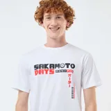 Remera blanca de manga corta con estampado gráfico frontal inspirado en el manga Sakamoto Days, con letras en negro y rojo y caracteres japoneses.